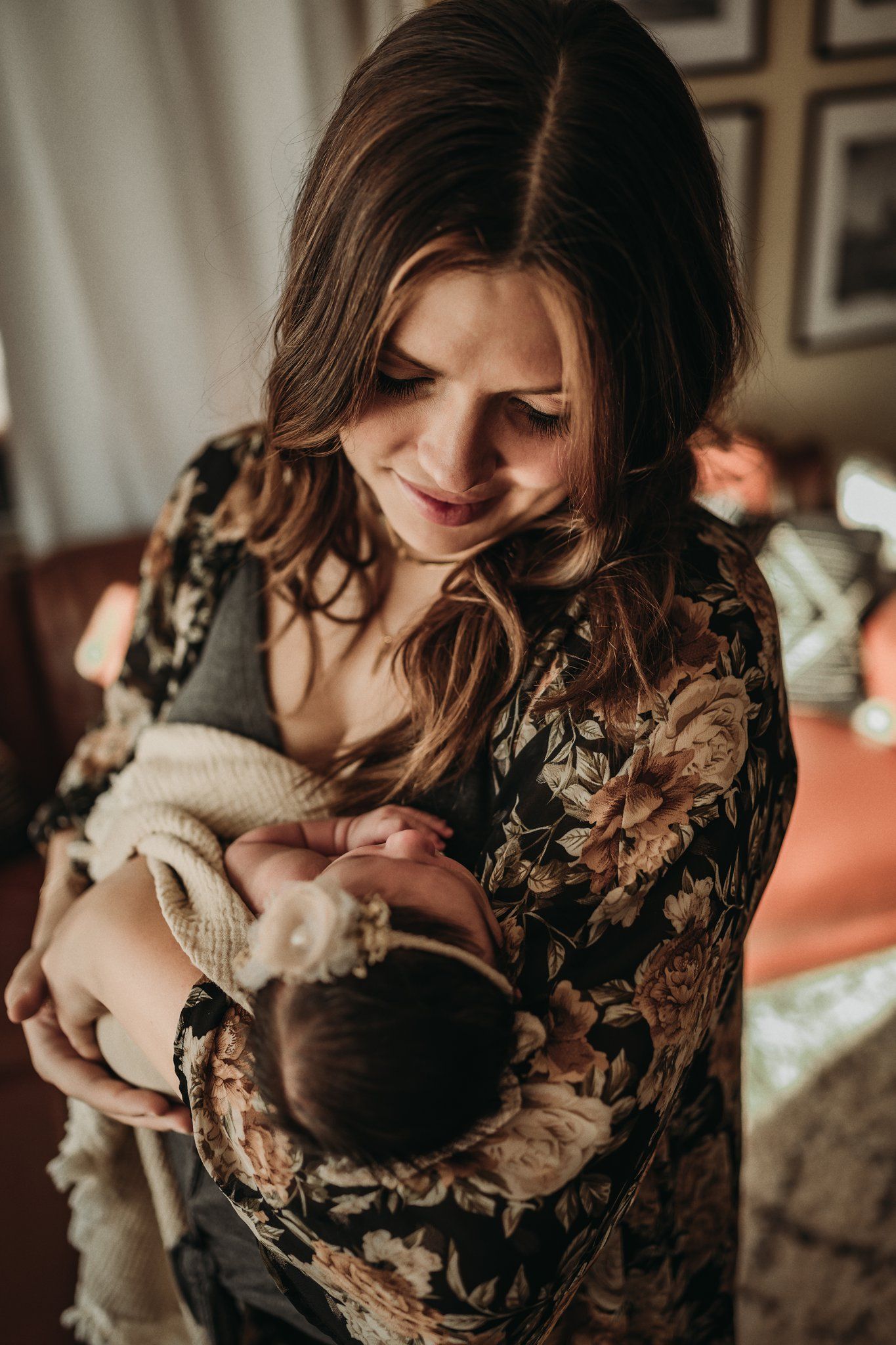 A tender moment between parent and newborn in a floral dress and knit blanket.