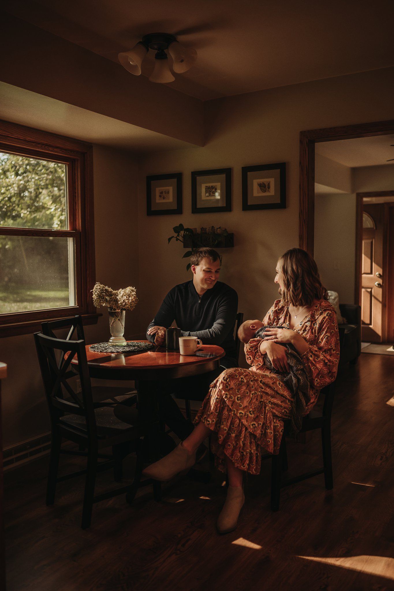 Sunlit dining room scene with couple sharing drinks at round wooden table.
