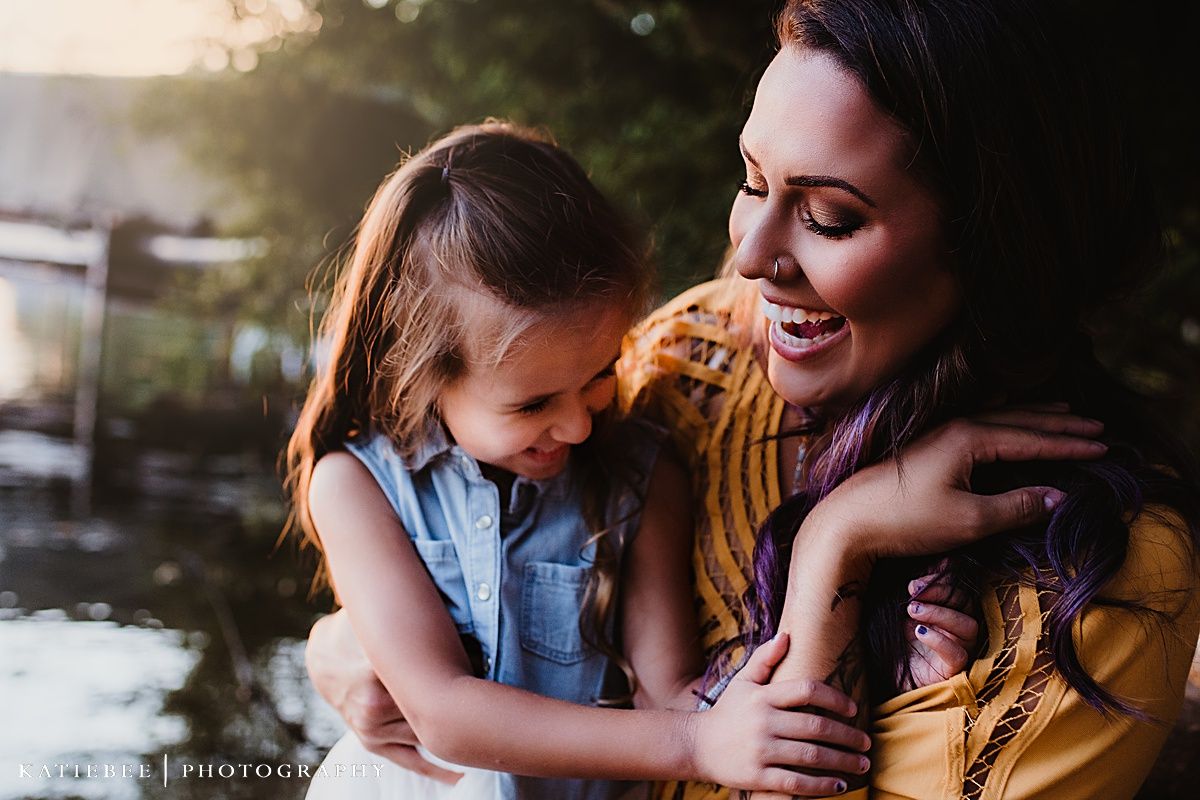 A tender moment of laughter and embrace by the water during golden hour.