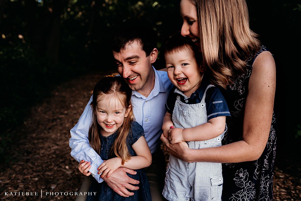 A joyful family shares laughter together during a forest photo session.