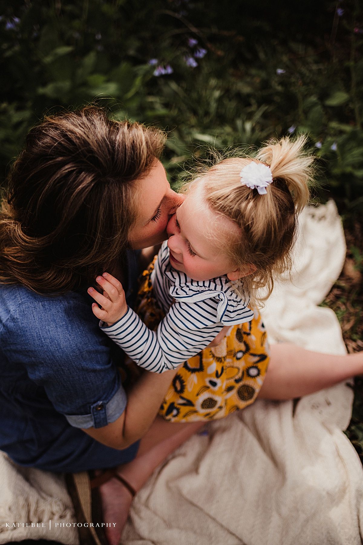 Intimate candid moment shared on a blanket surrounded by greenery.
