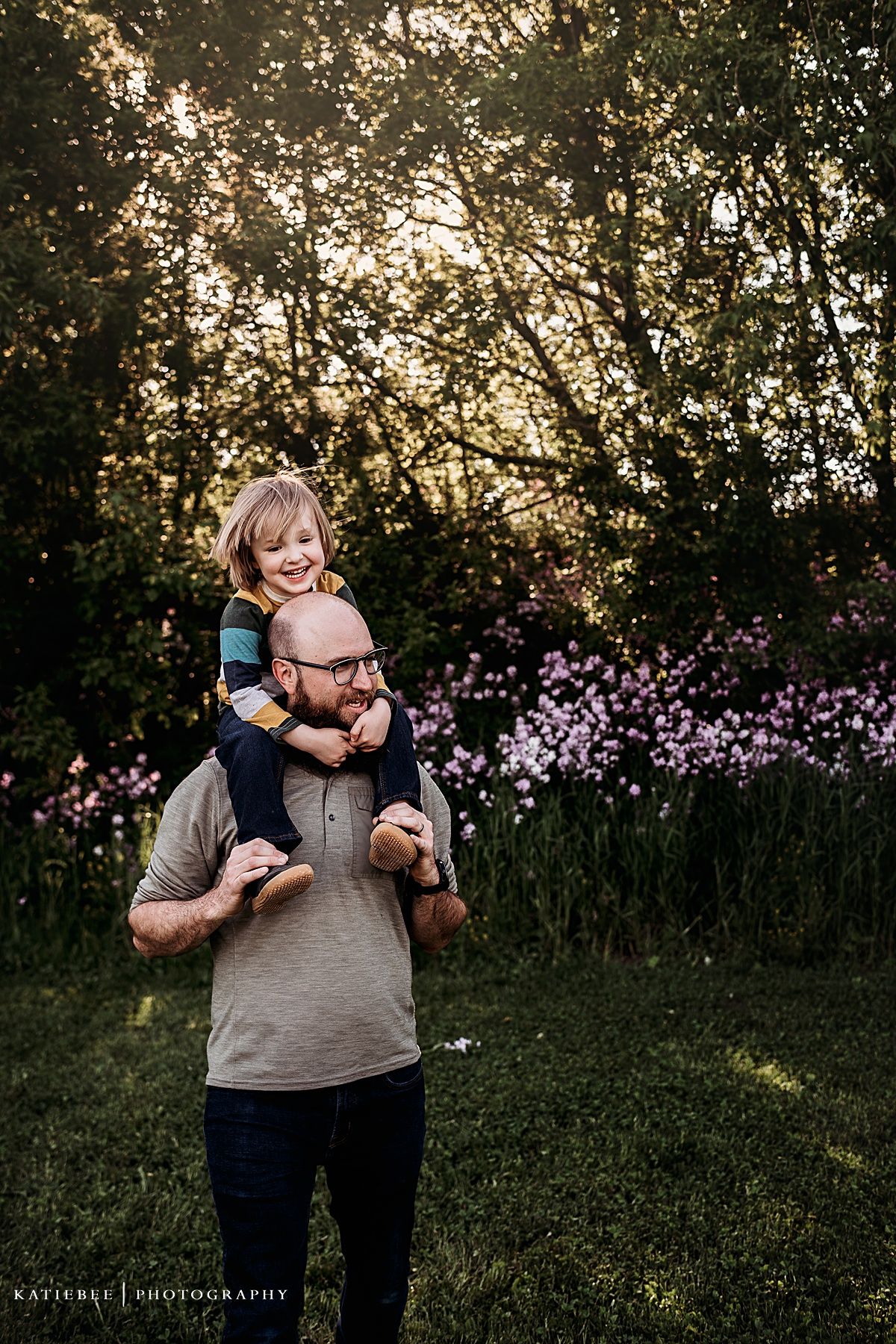 A heartwarming sunset portrait taken in a garden with purple flowers blooming in the background.