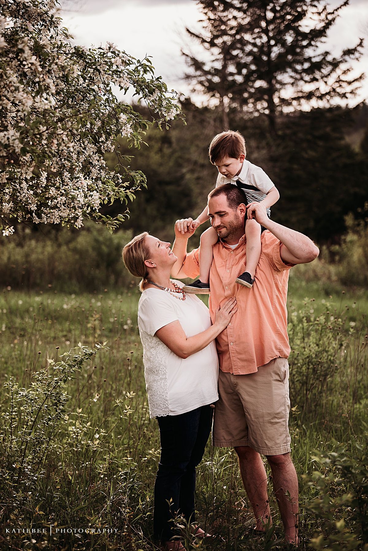 A family shares a joyful moment together under flowering trees in a spring meadow.