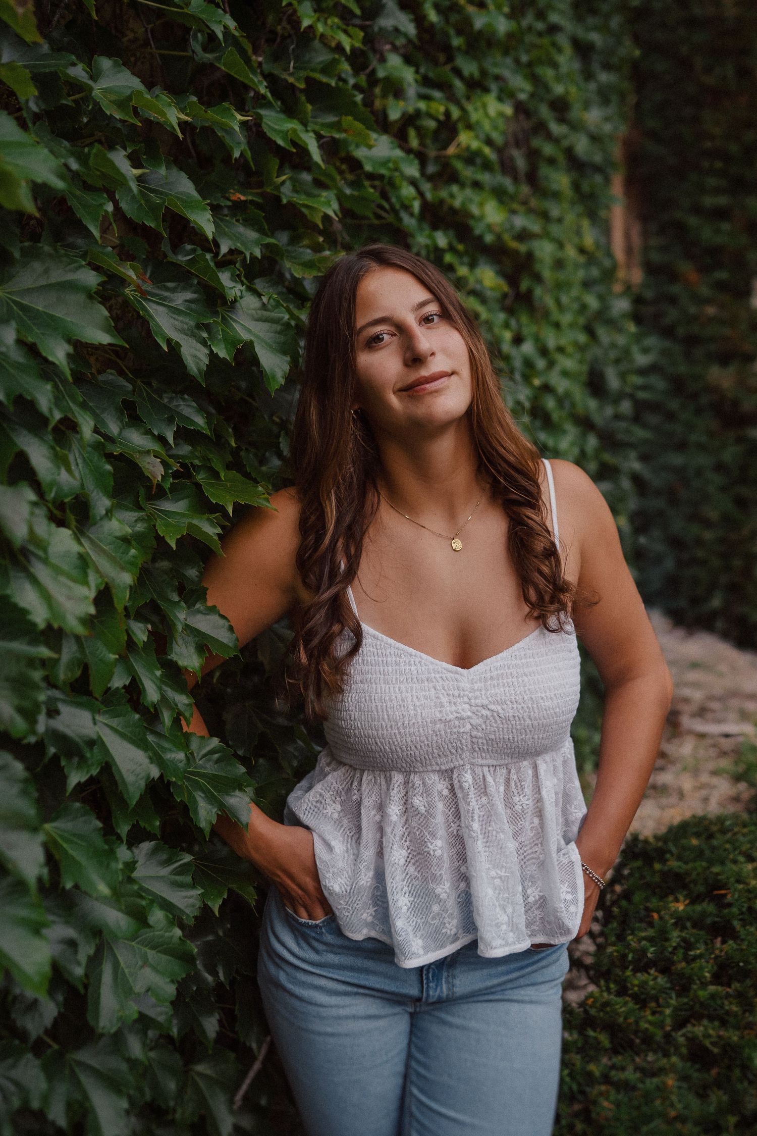 Summer fashion portrait against a backdrop of climbing ivy and green leaves.