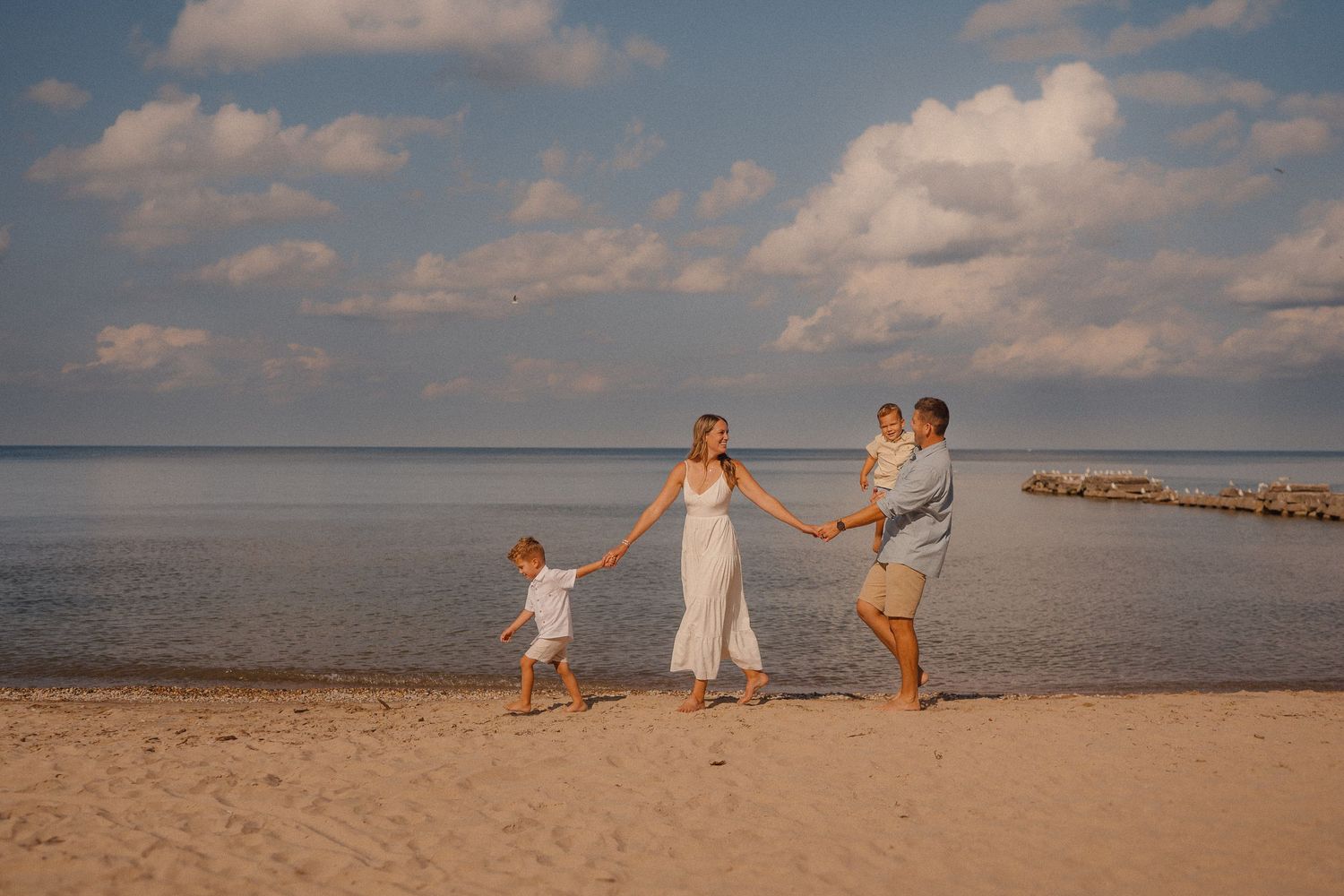 Candid moments captured at the beach with water and cloudy sky in background.