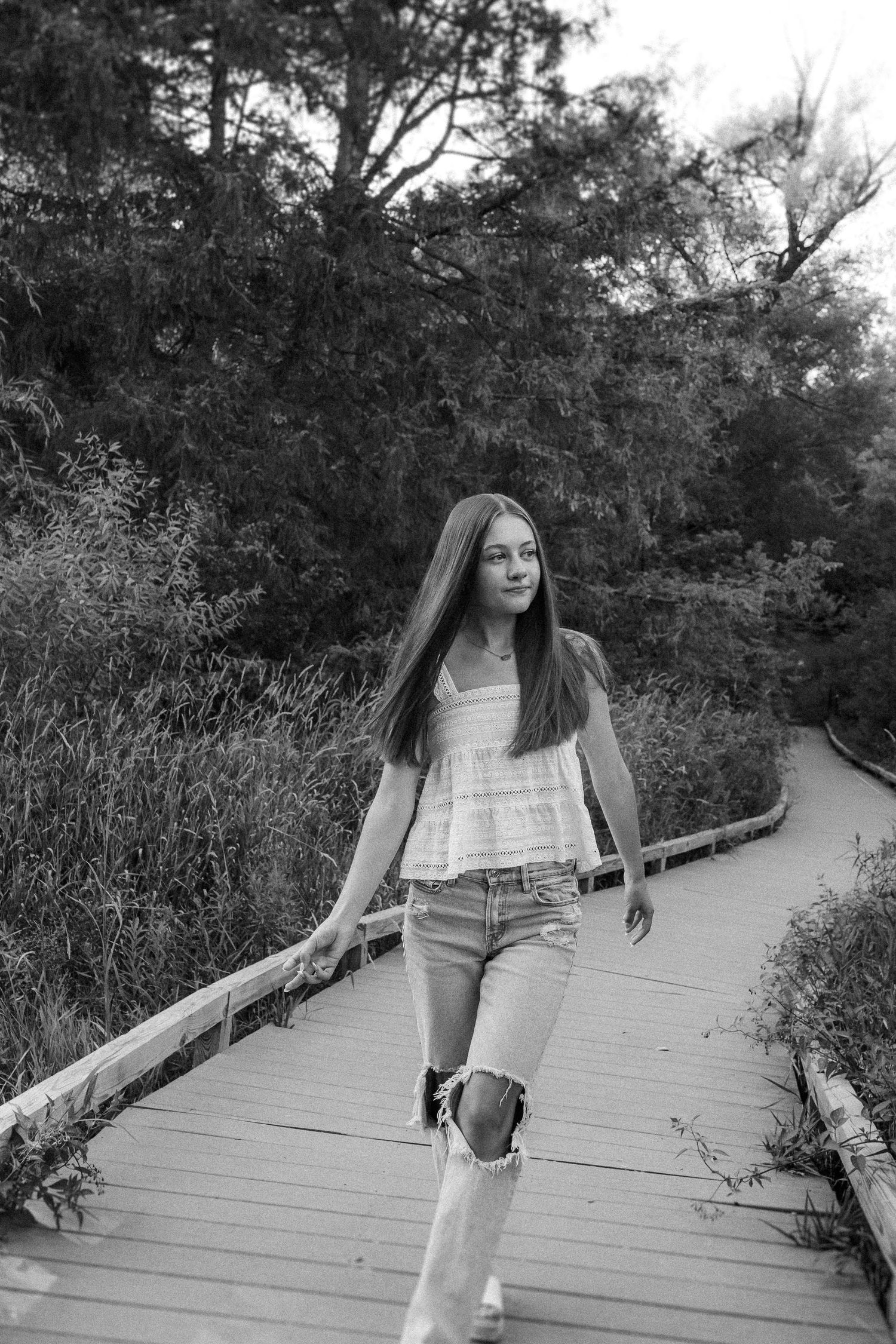 Black and white photo captured on a wooden boardwalk with natural foliage on both sides.