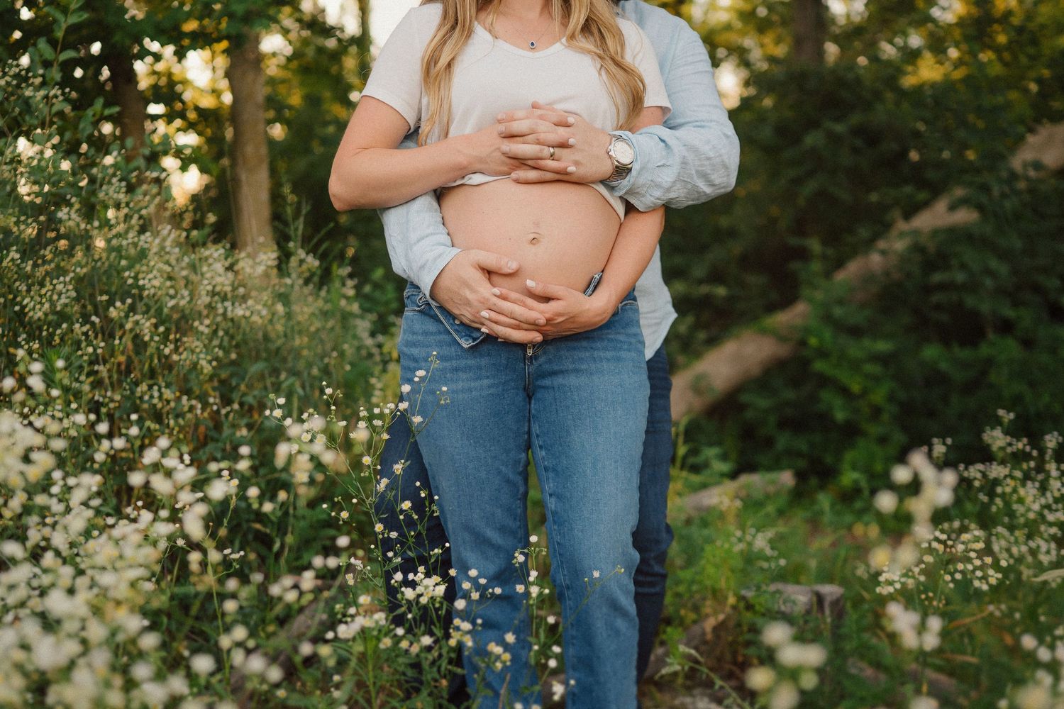 Close up shot of a couple holding each other tenderly in a flowery outdoor setting.