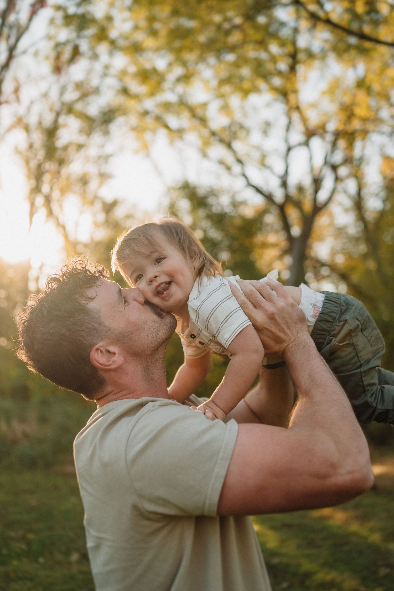 Heartwarming outdoor sunset moment of playful interaction between parent and child surrounded by autumn trees.