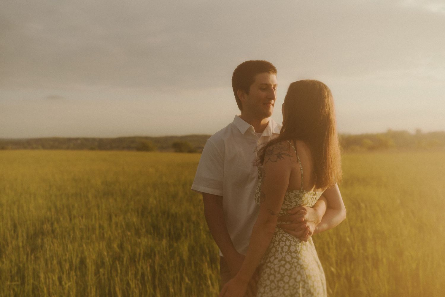 A backlit silhouette of a couple embracing in a golden wheat field during sunset.