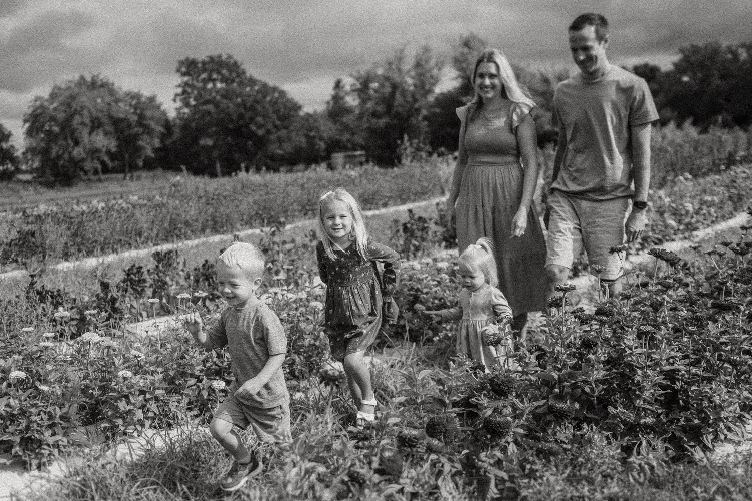 Black and white photo of a group walking through a flowering meadow.