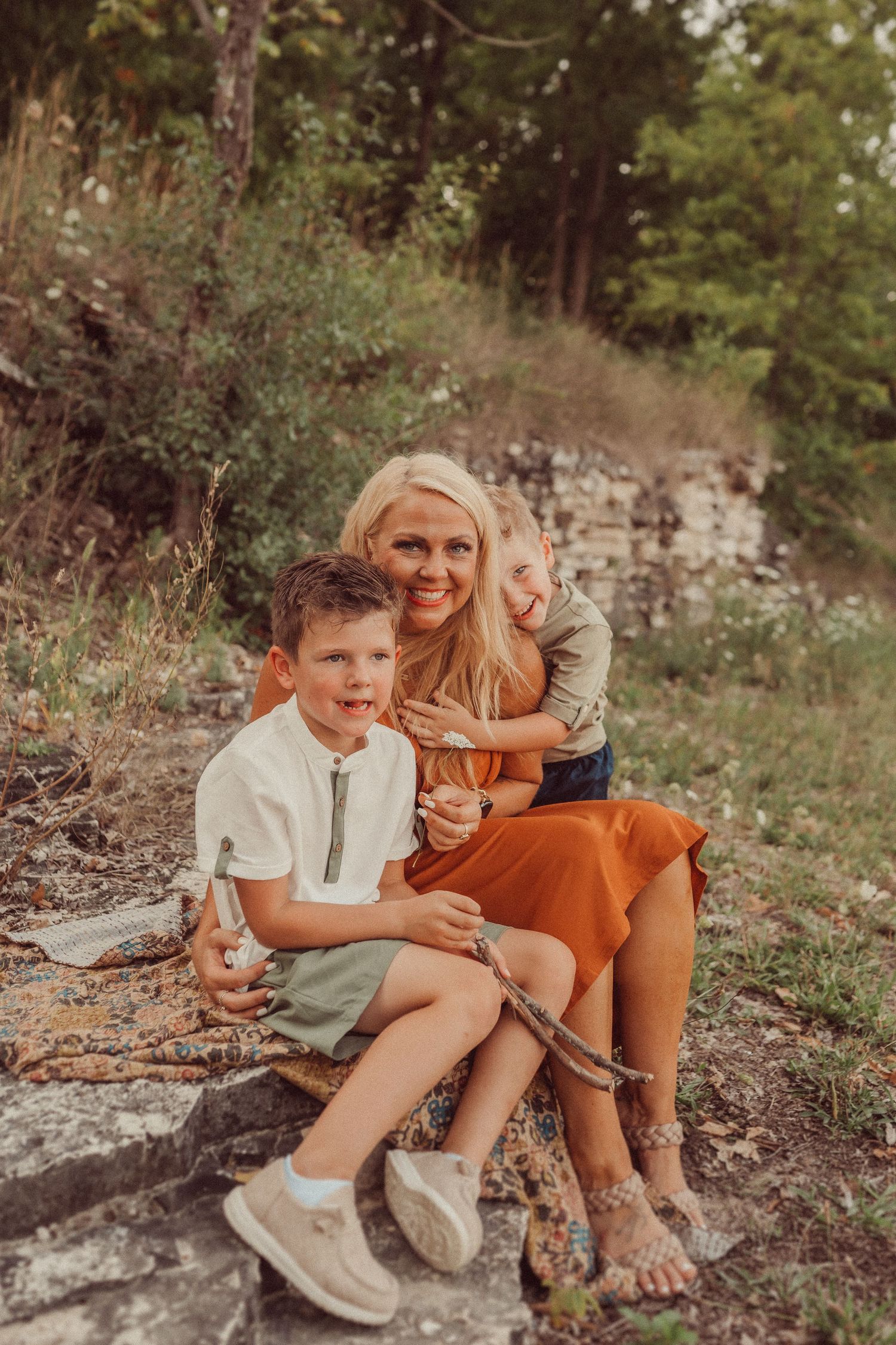 A warm sunset photo captures a tender family moment on rocky terrain.