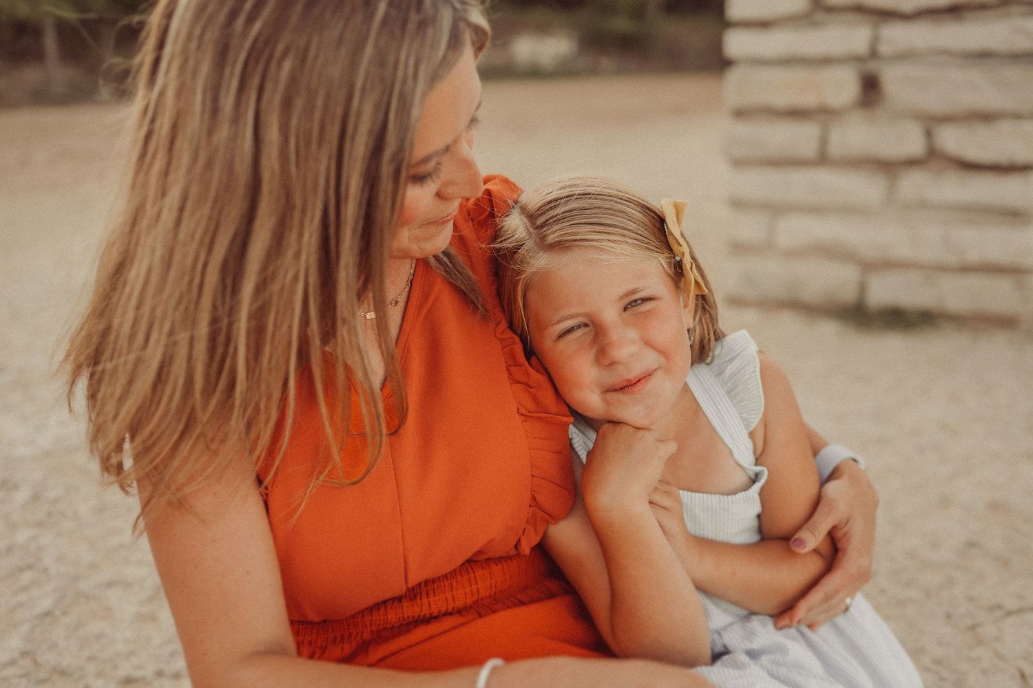 Warm sunset portrait showing genuine smiles and affection against a stone pillar backdrop.