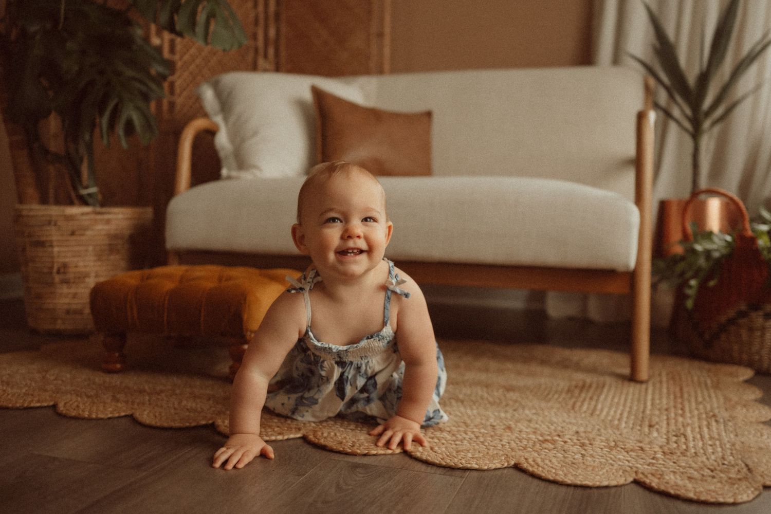 A joyful toddler crawls on a round jute rug near houseplants.