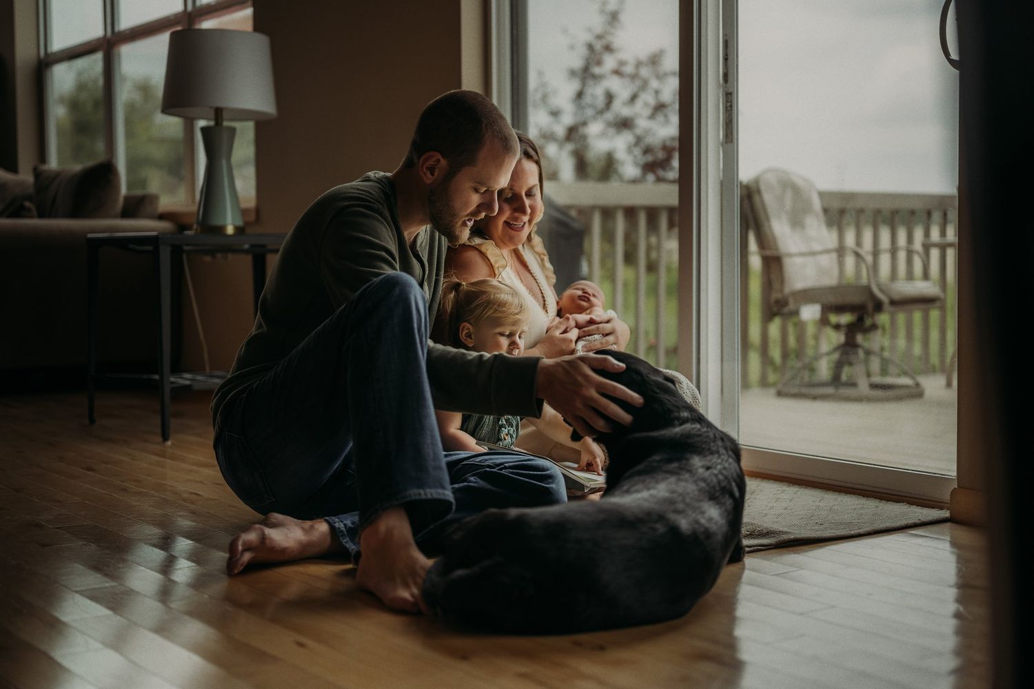 Intimate moment with black dog and family members by sliding glass door.