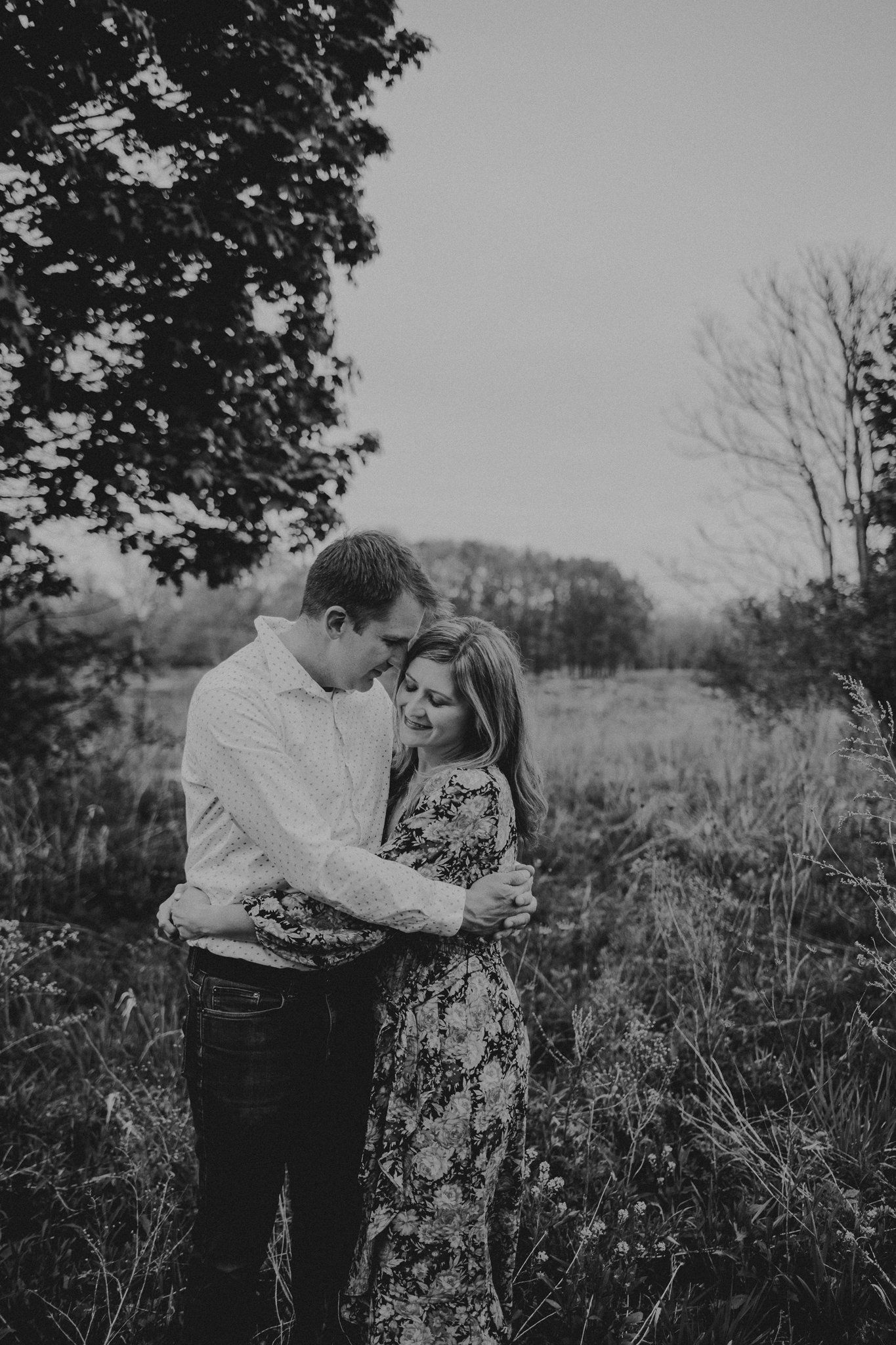 A romantic black and white portrait in a serene natural setting with tall grass.