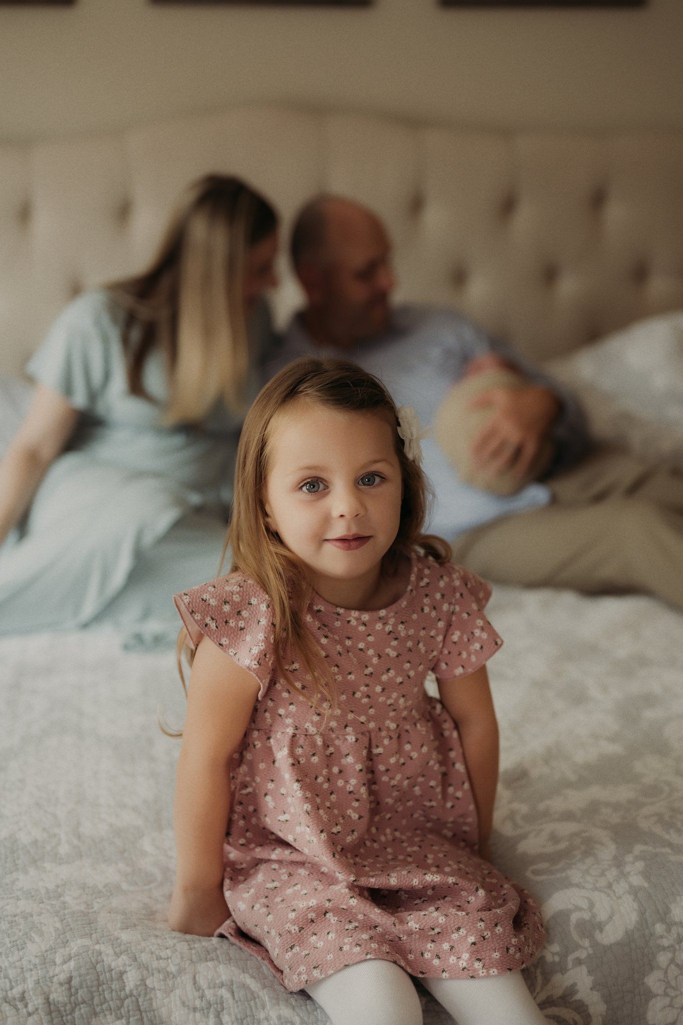 A sweet moment captured on a light beige tufted headboard bed showing family relaxing together.