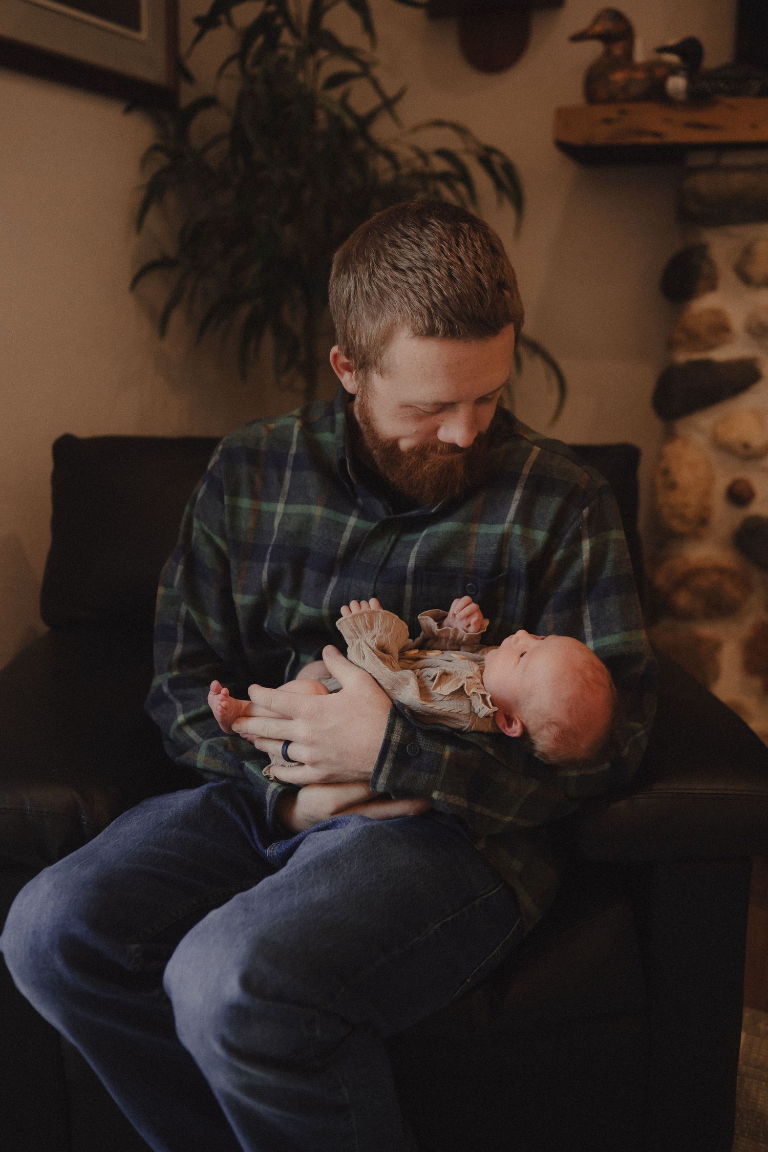 A tender moment of bottle feeding a baby in a dimly lit room with a cozy atmosphere.