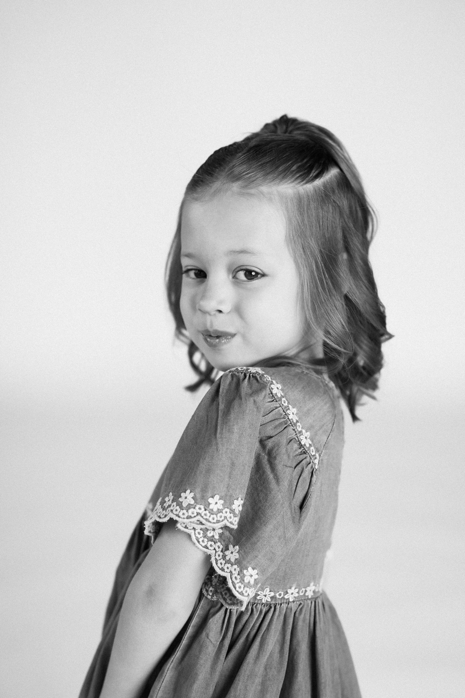 Black and white portrait series showing playful expressions and a gray dress with lace detail.