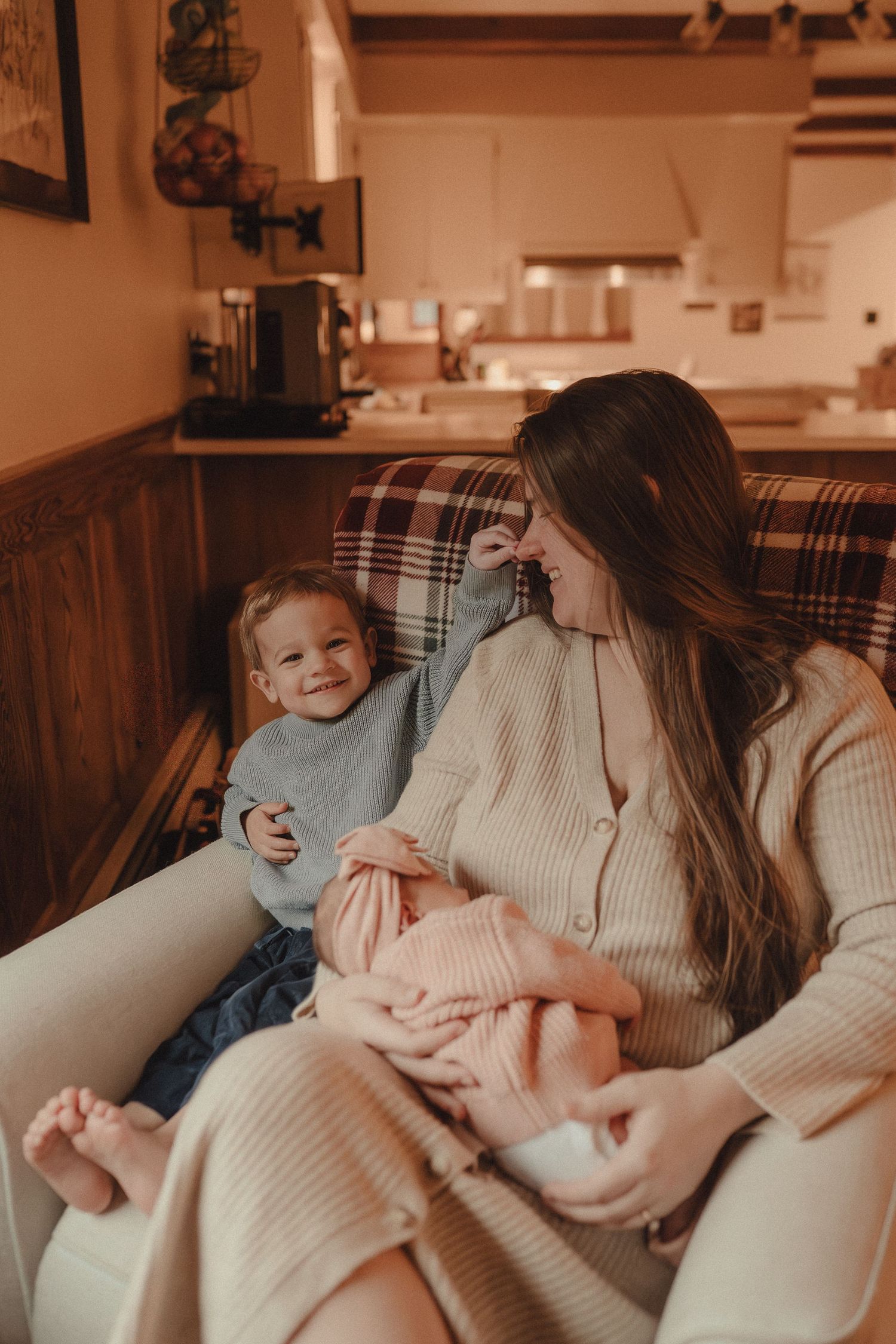 Family relaxing together on a plaid couch in a cozy living room setting.
