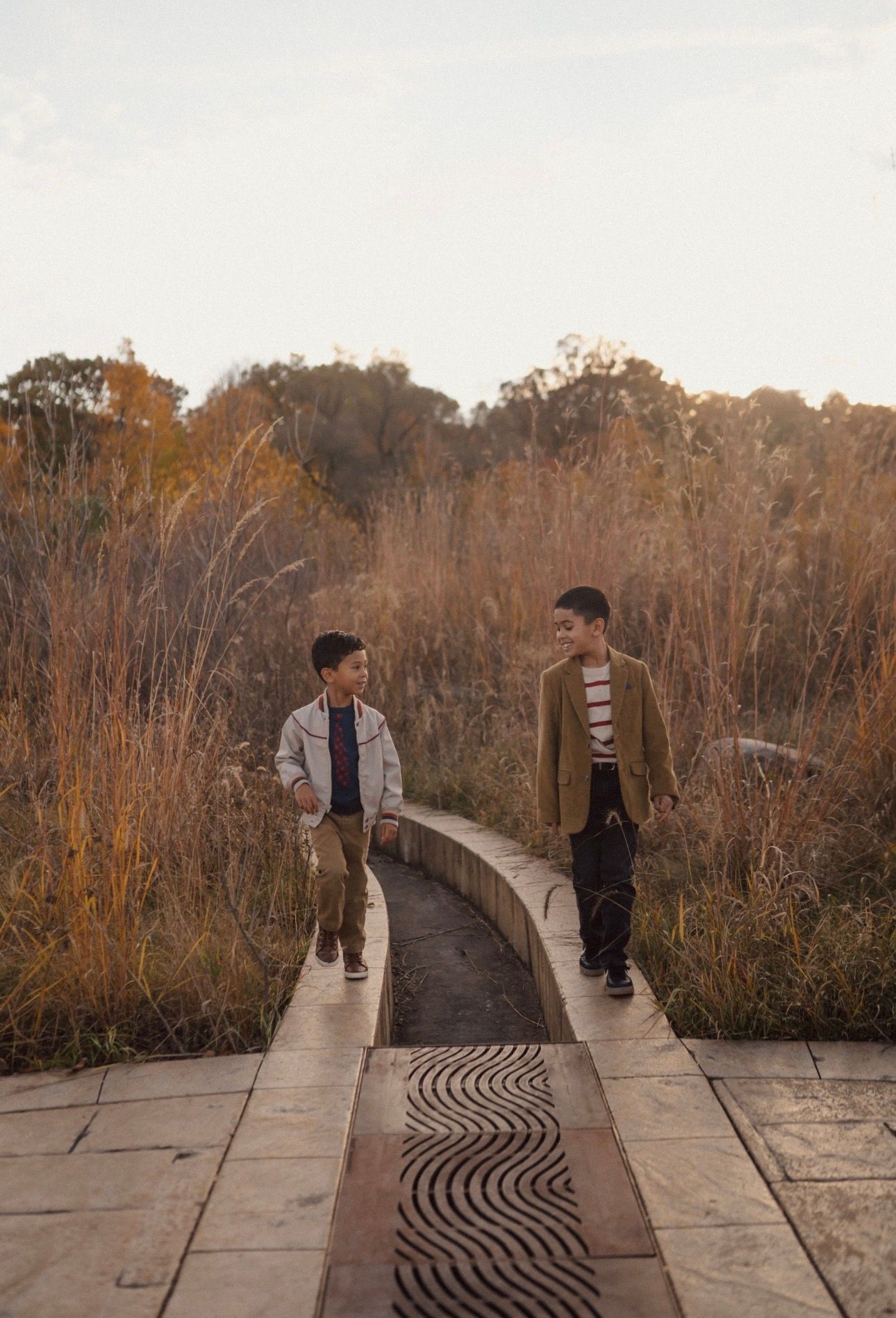 People walking along elevated wooden boardwalk through autumn marsh landscape.