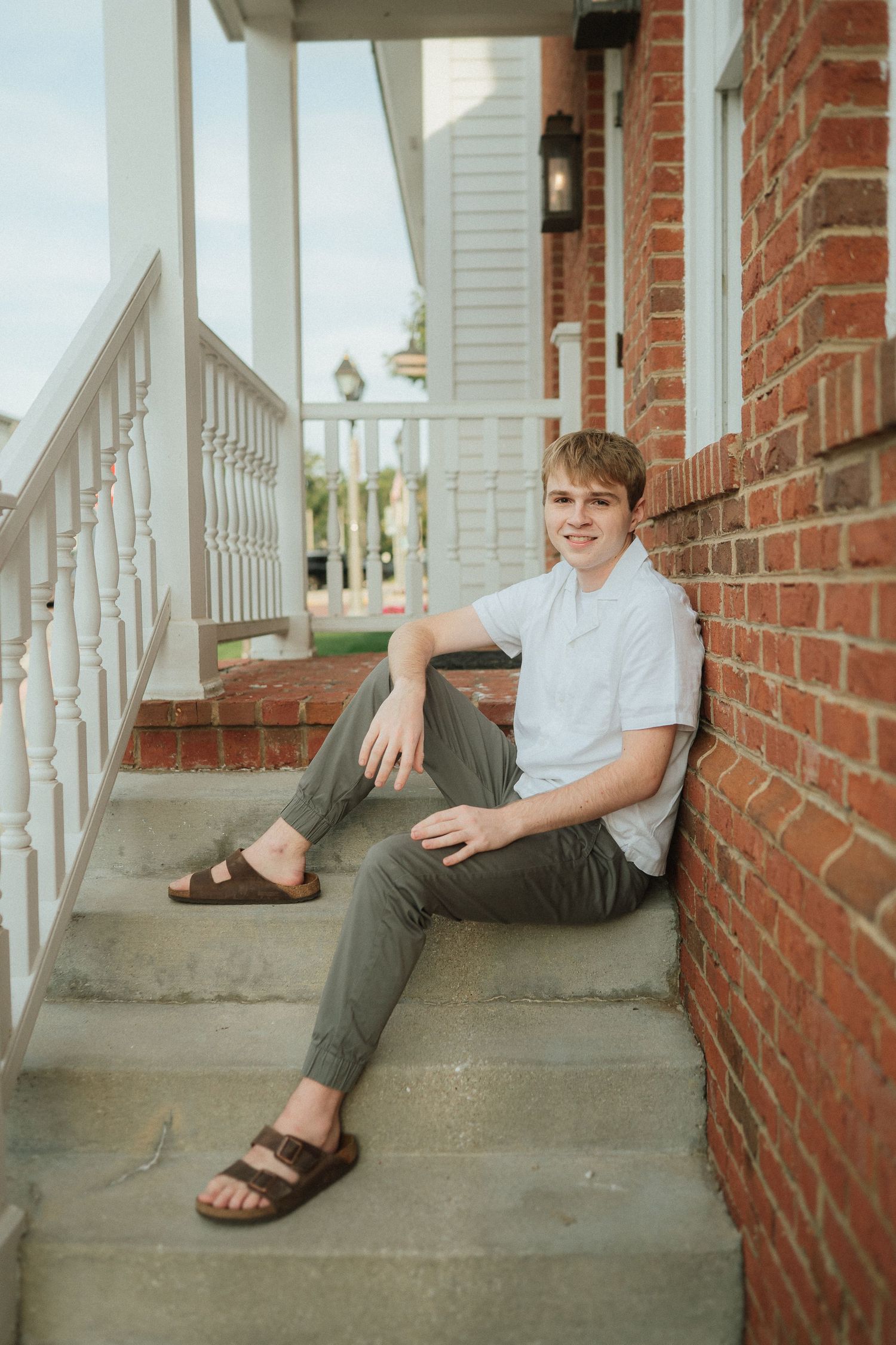 A sequence of casual portraits showing someone sitting and relaxing on concrete steps against a red brick wall.
