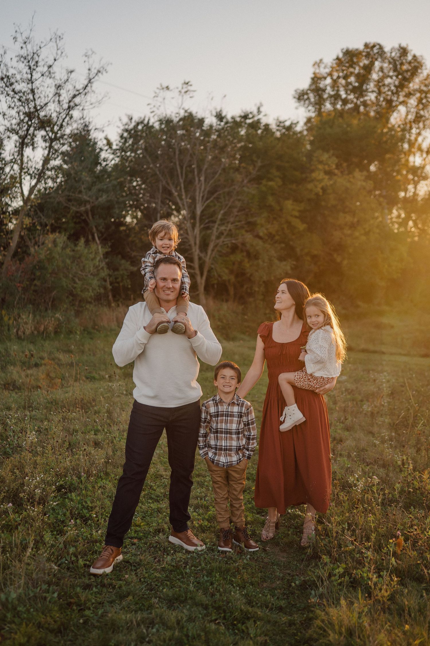A candid family moment captured in a natural outdoor setting during sunset.