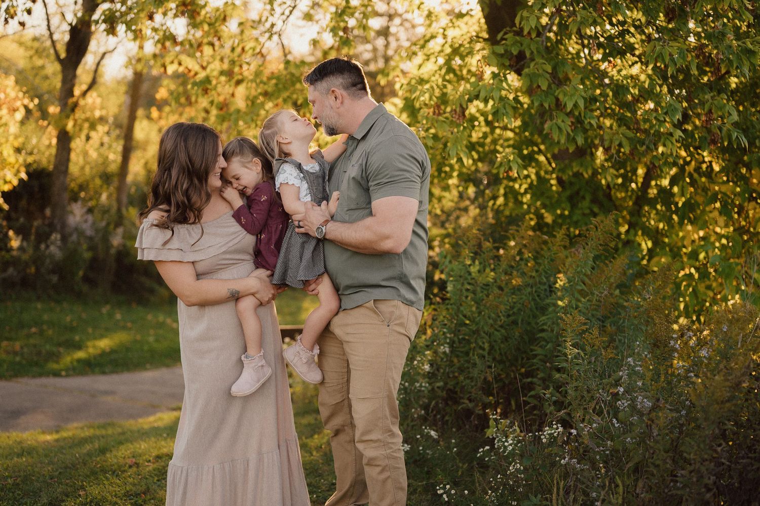 A family shares a tender moment together in a sunlit garden setting during golden hour.