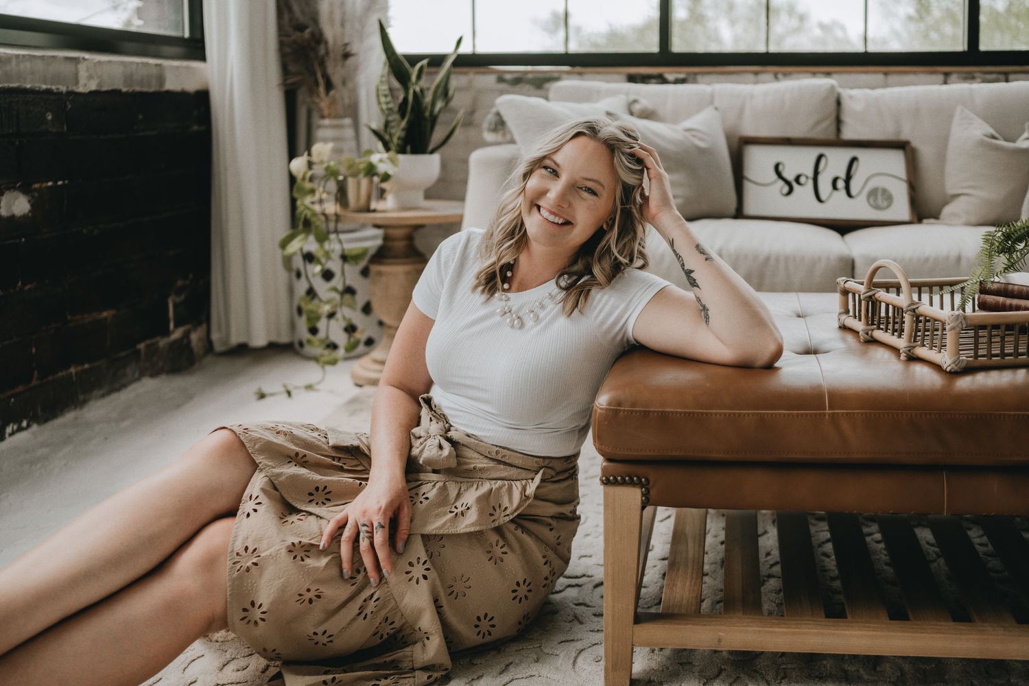 Casual portrait in sunlit living room with leather furniture and decorative pillows.