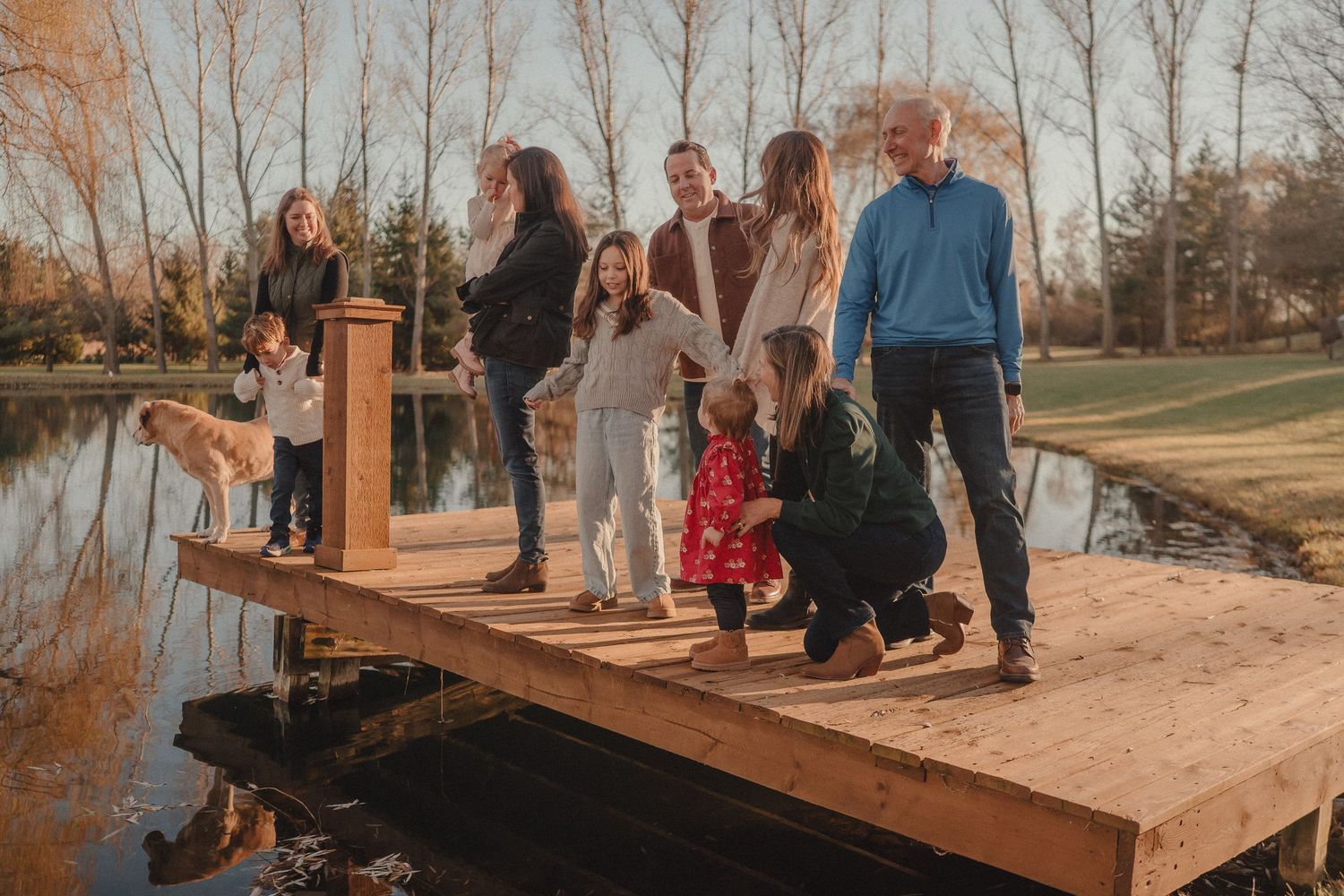 Group gathered on wooden deck or boardwalk during outdoor family photography session at sunset.