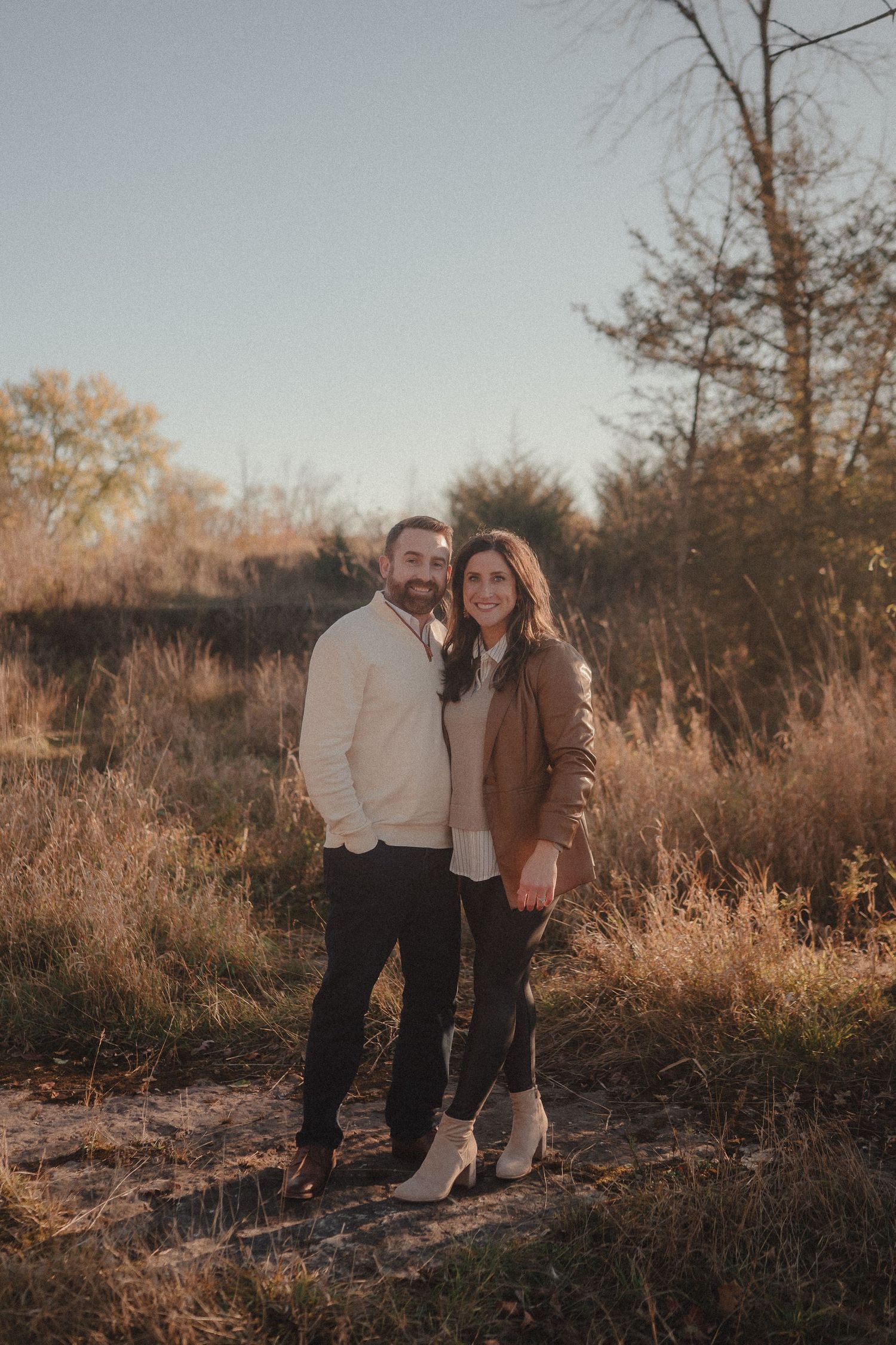 Family portrait session in golden hour light with autumn grasses and trees in the background.