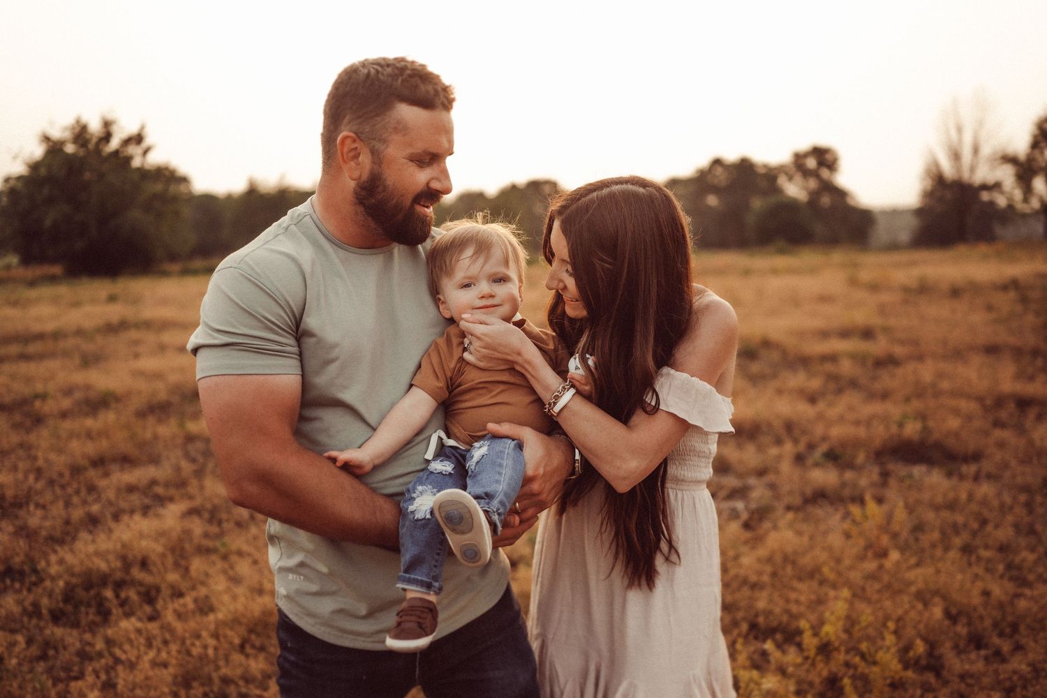 A family shares an intimate moment together at sunset in a golden field.
