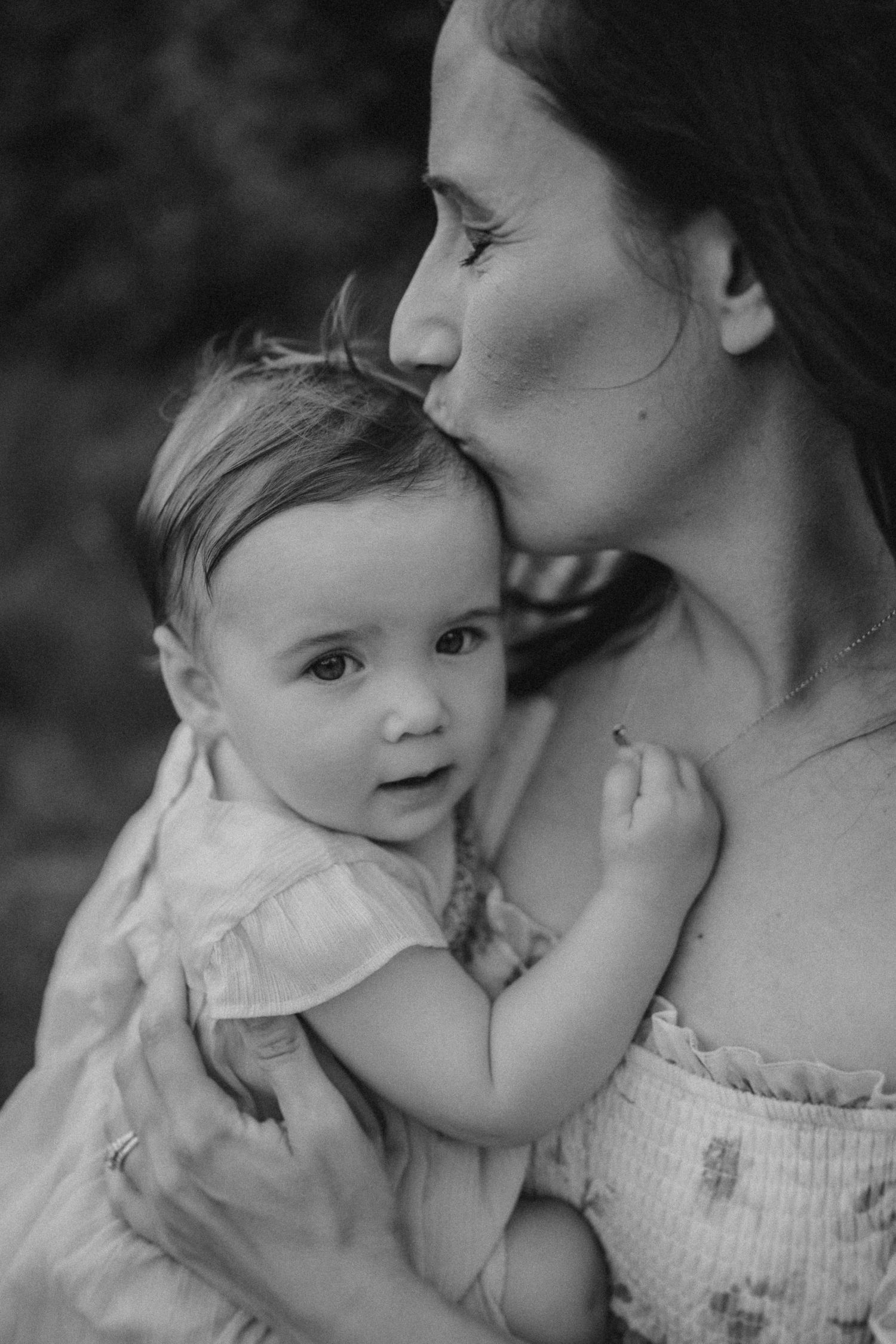 An intimate black and white portrait showing a tender maternal moment.