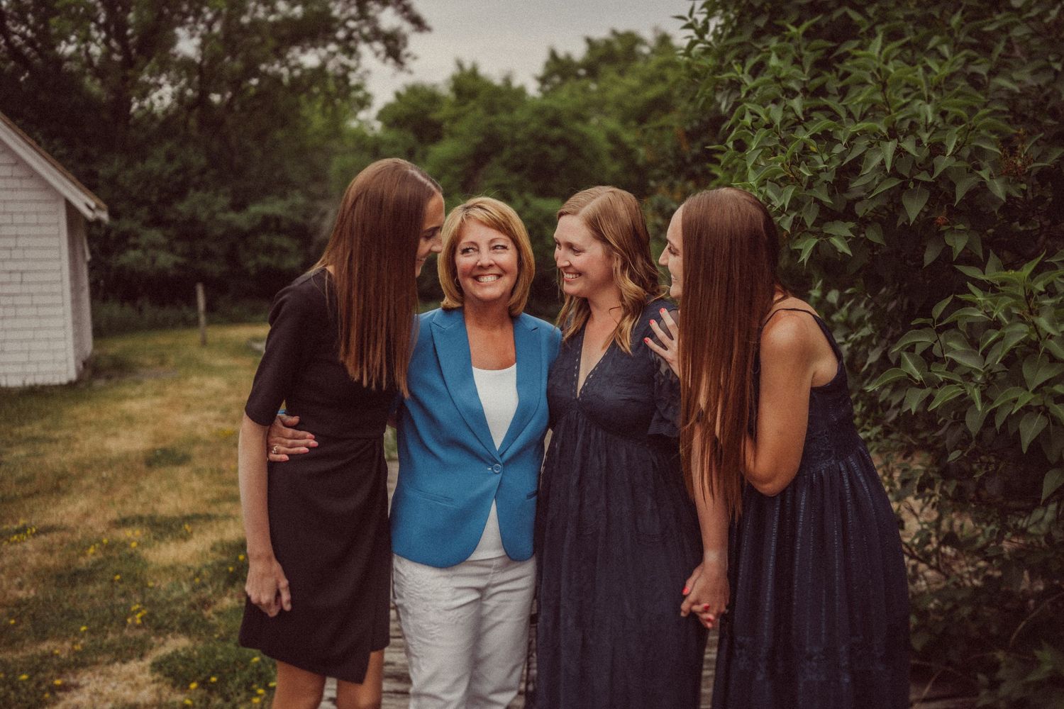 Four women sharing joyful moment together outdoors on summer day.