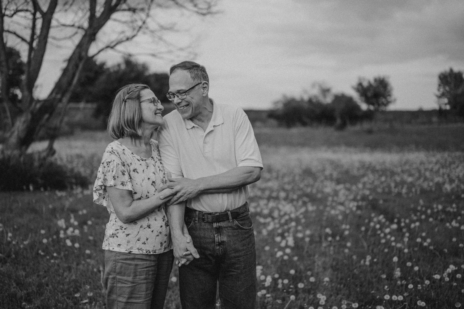 A couple shares an intimate moment in a meadow with wildflowers, photographed in monochrome.