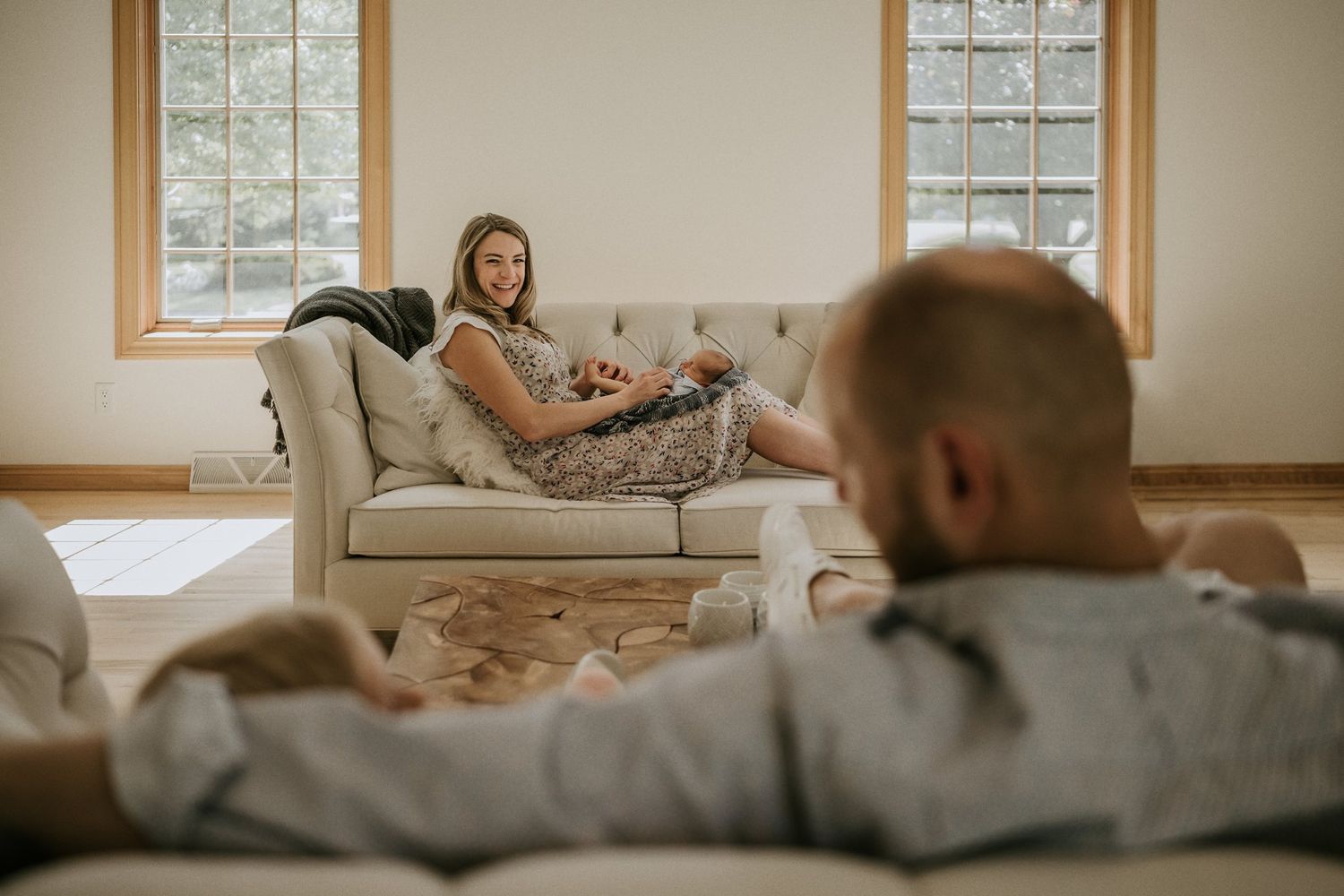 Cozy home scene with two people relaxing on separate couches in a sunlit living room.