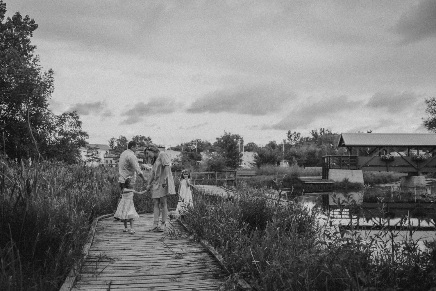 Black and white photo of people walking on a wooden boardwalk through natural wetlands.