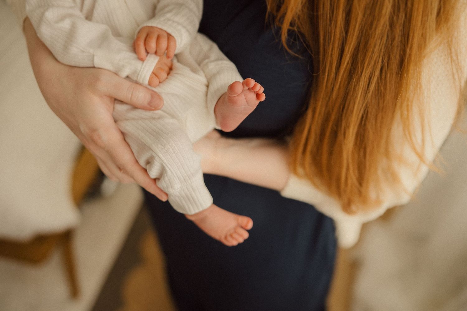 Close-up shot of tiny newborn baby feet being held by gentle hands.