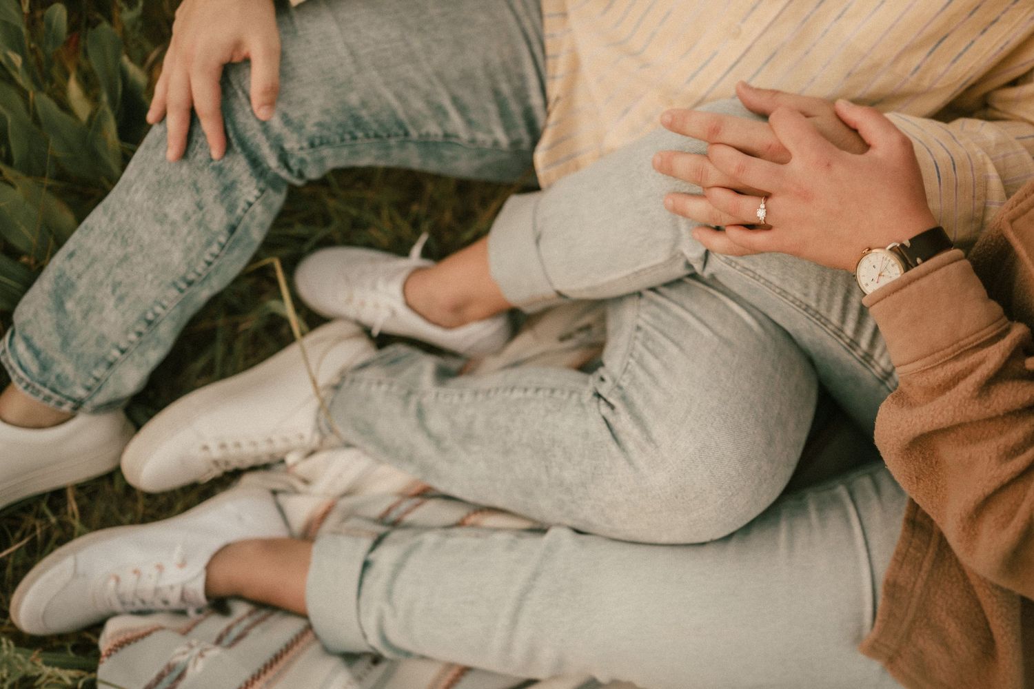 A tender moment captured showing feet and hands resting together on a cozy surface.