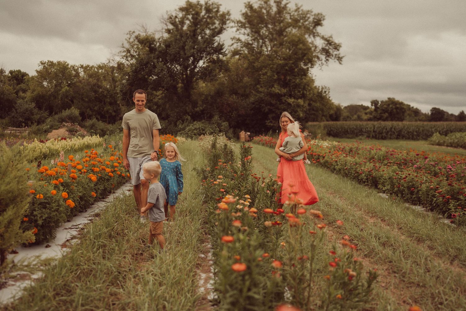 Family walking along a garden path surrounded by blooming orange flowers.