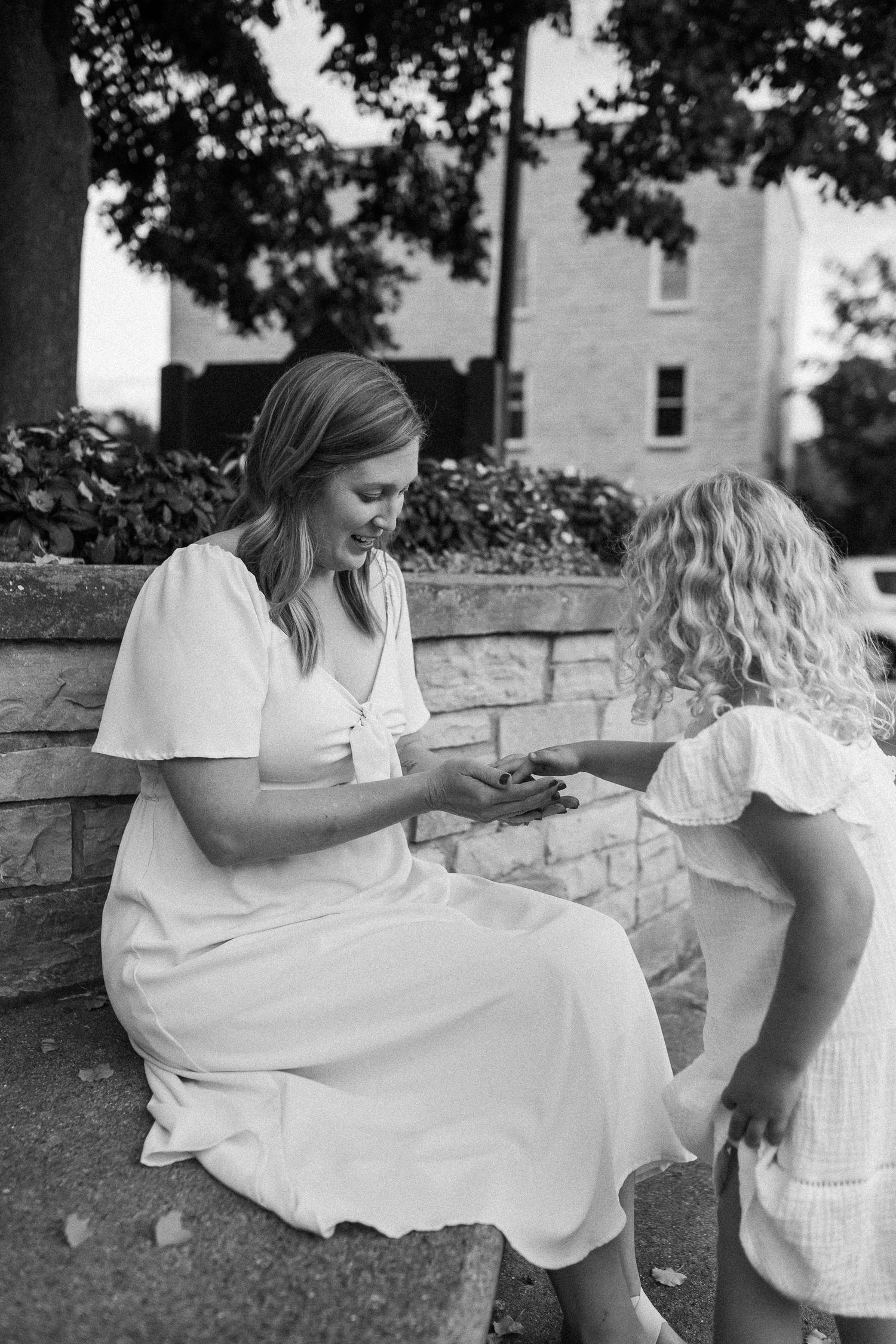 People sitting together on a stone wall in white summer dresses.