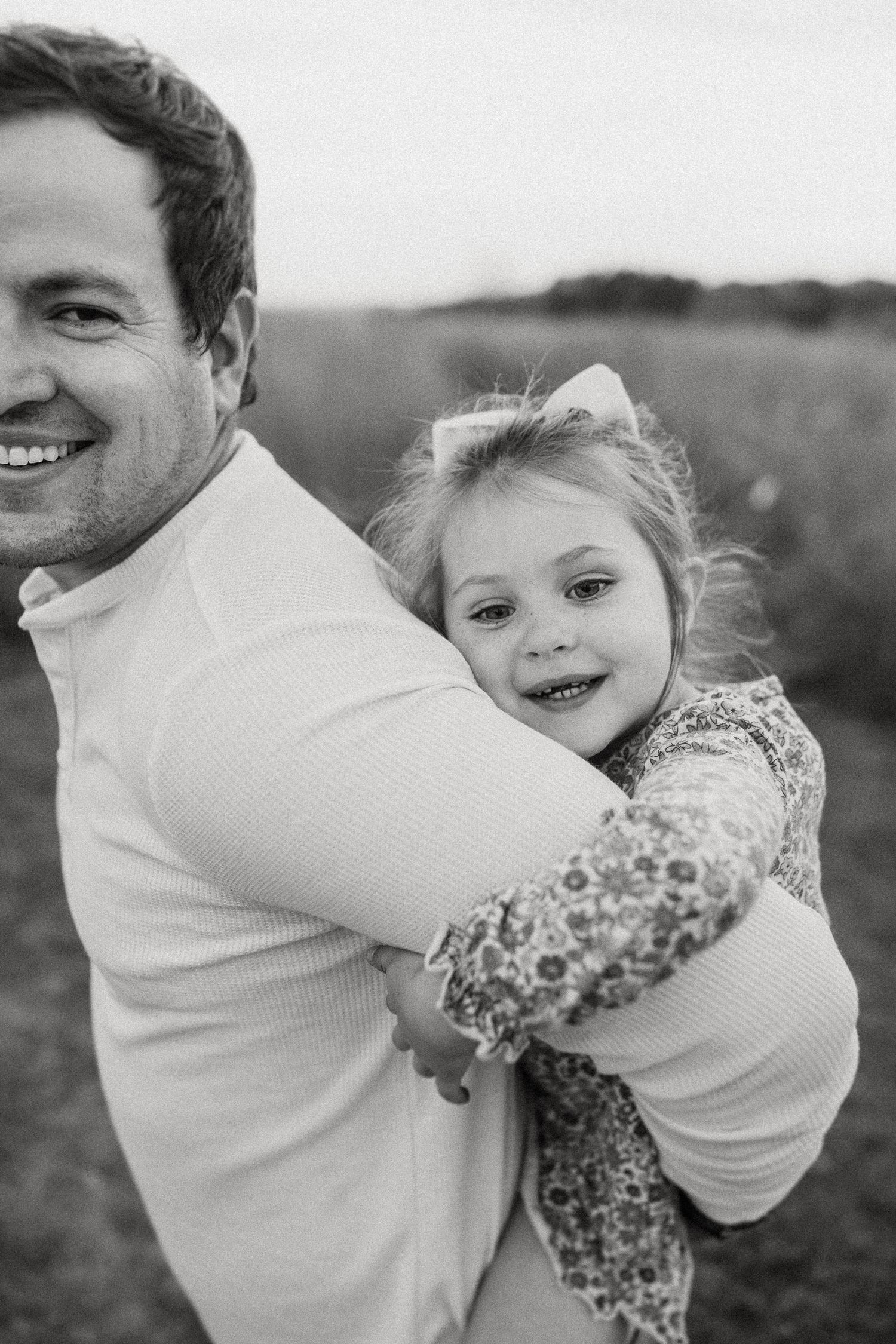Close-up black and white portrait showing joy and laughter in a natural outdoor setting.