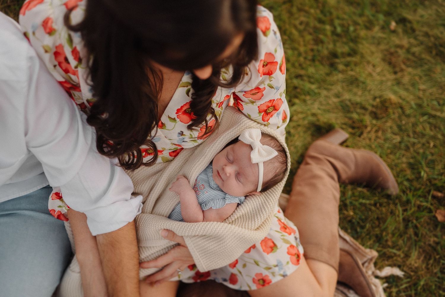 A peaceful scene of a caregiver holding a swaddled baby on a sunny day outdoors.