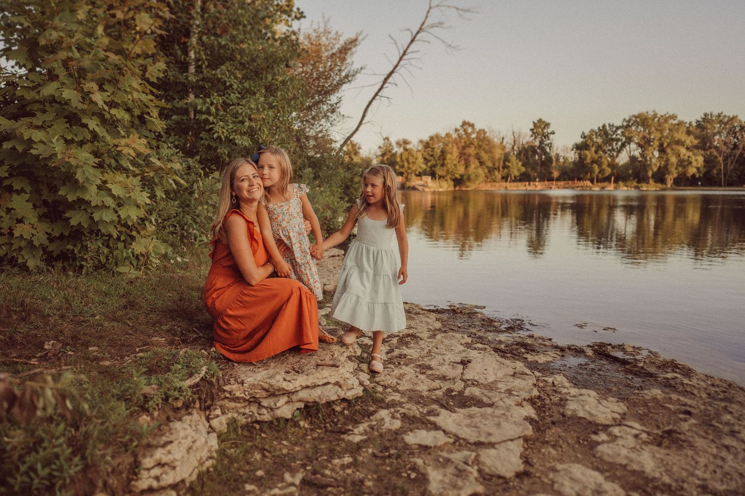 Warm sunset portrait by the lake with fall trees in the background.