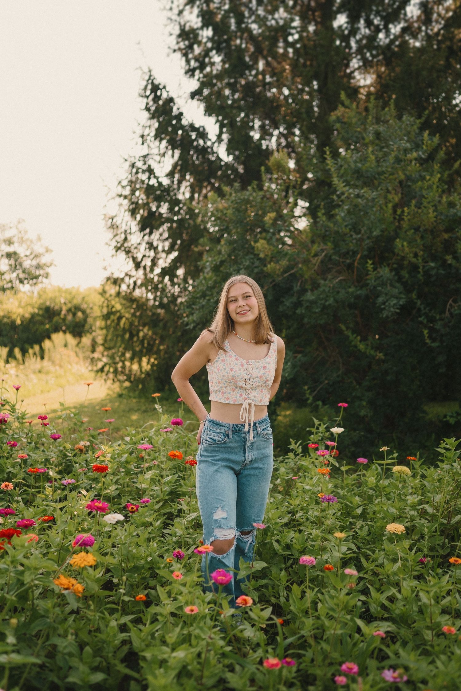 A casual summer portrait in a blooming flower garden with pink and orange zinnias against green foliage.