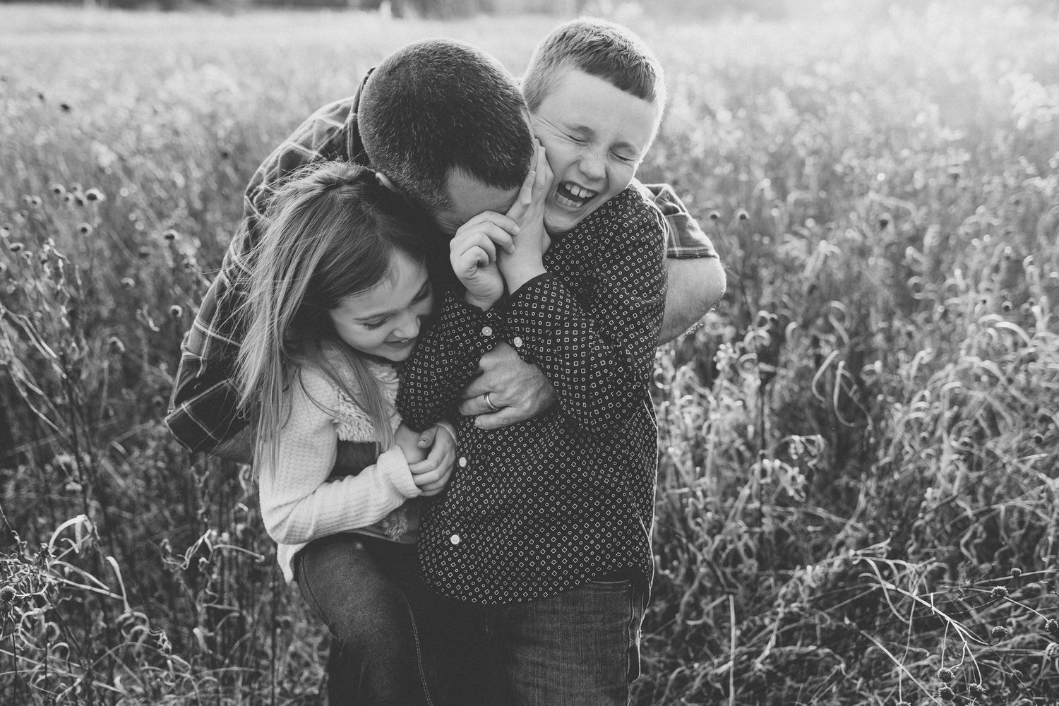 Black and white capture of a family sharing a playful moment in nature.