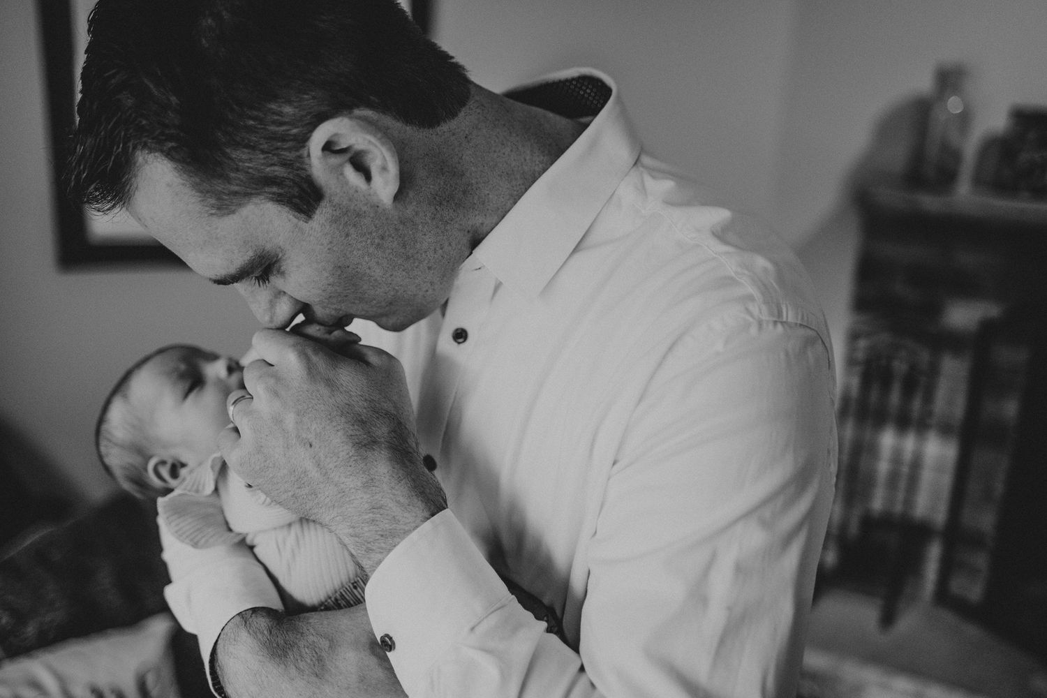 Black and white photograph capturing intimate moment between parent and baby.