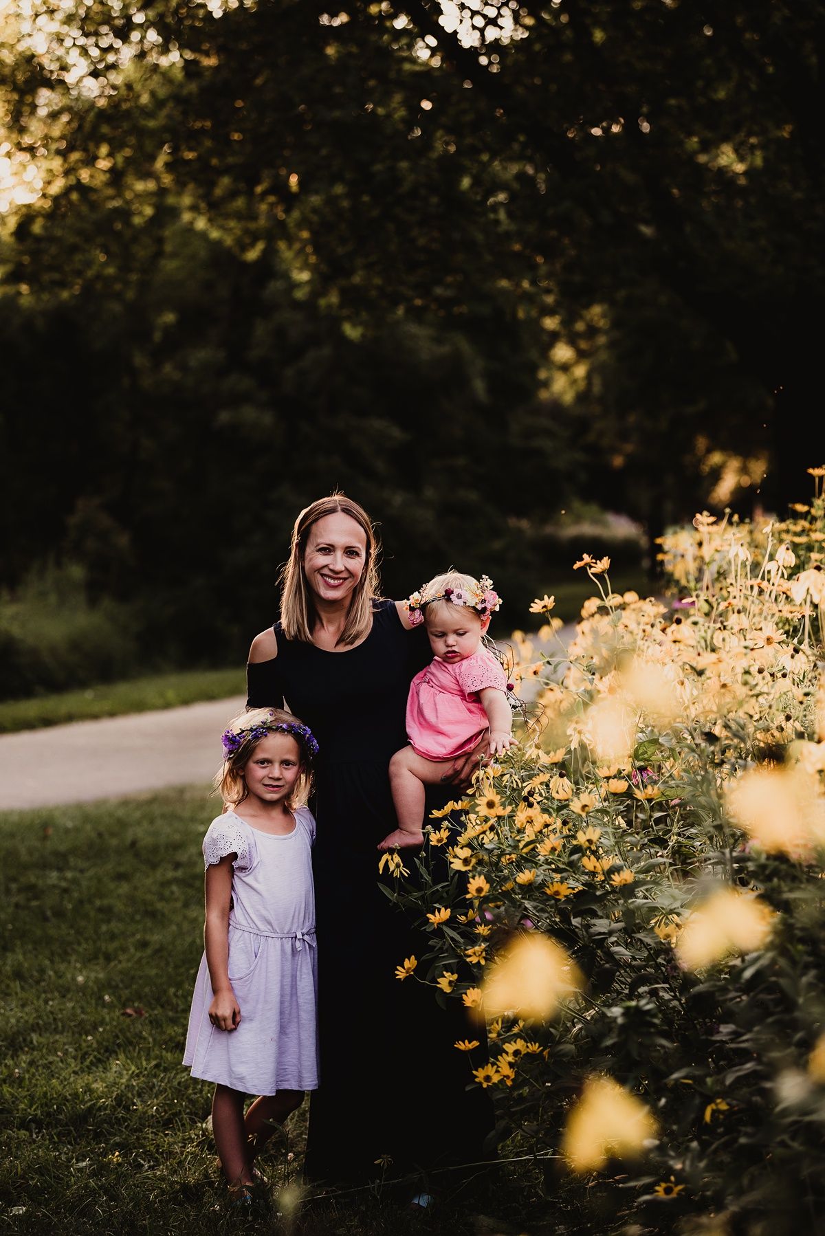 Outdoor family portrait with golden flowers and evening sunlight creating warm atmosphere.