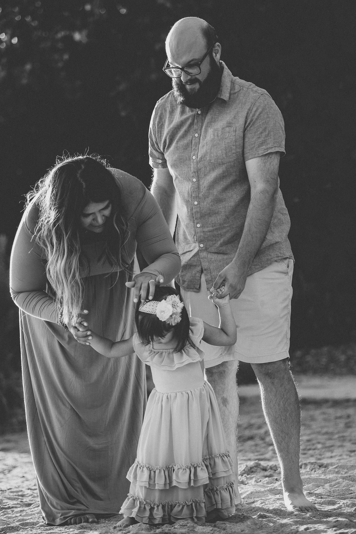 Black and white candid family moment captured on a beach.