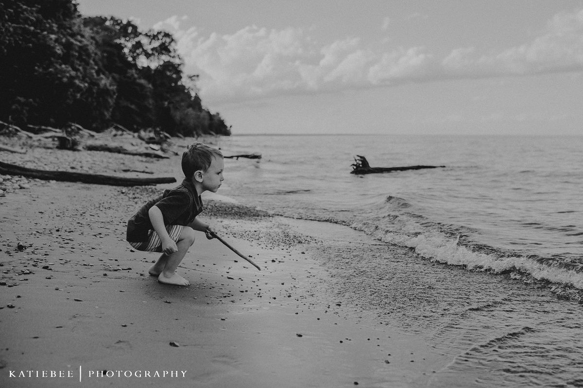 A black and white image of a child playing at the beach shoreline.