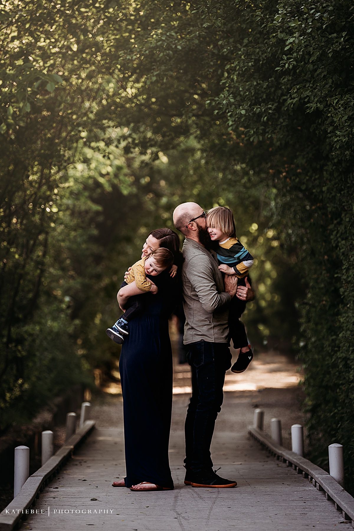 Family standing on garden path surrounded by trees and golden sunlight.